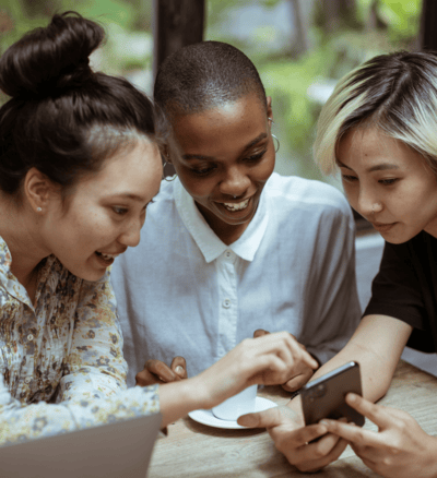 3 unge kvinder kigger på telefon